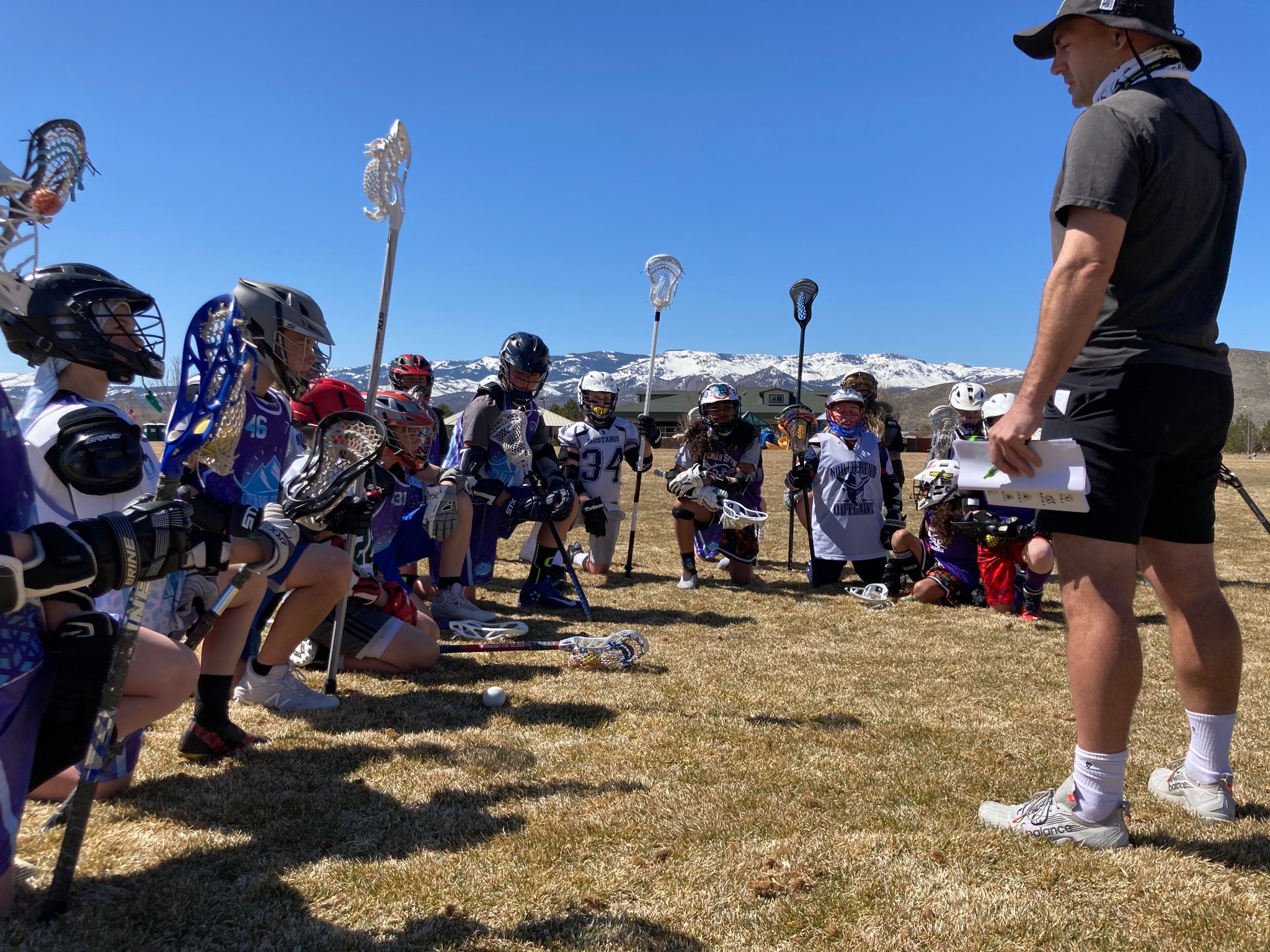 Coach leading a free community lacrosse clinic for boys and girls.